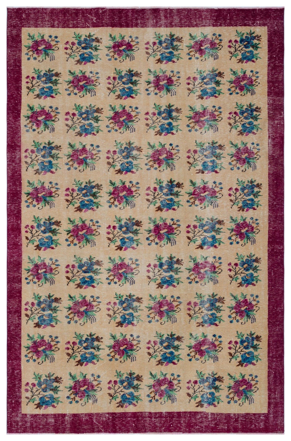 Beige rug with a repeating floral pattern in magenta and blue, framed by a wide, distressed magenta border.