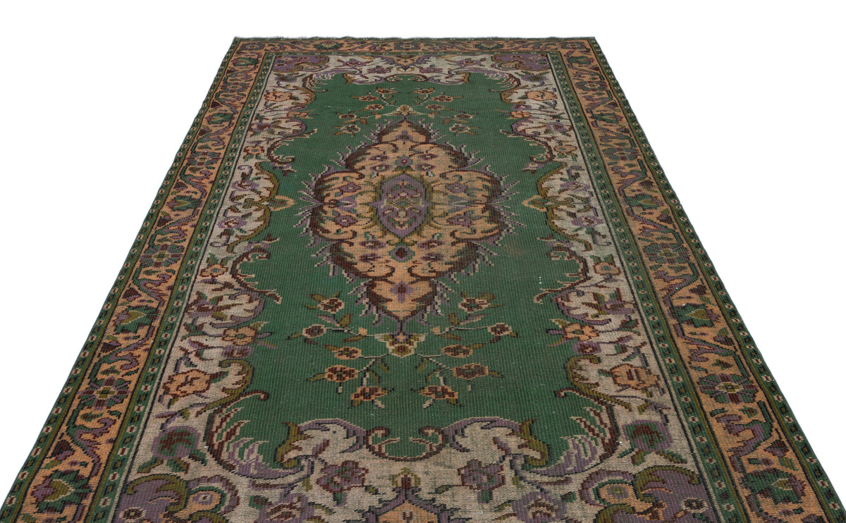 Emerald green traditional rug with a central floral medallion and ornate border in muted purple, tan, and brown tones.