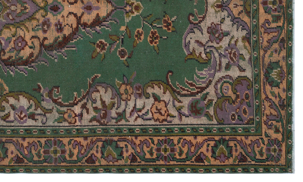 Green traditional rug with a floral medallion pattern in peach, purple, and beige, featuring a detailed border.