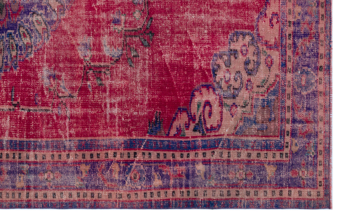 Distressed magenta and purple vintage-style rug with a faded floral medallion pattern and a decorative border.