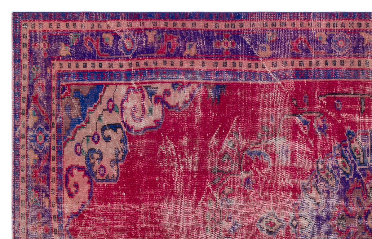 Distressed magenta and purple vintage-style rug with a traditional floral border and medallion pattern.