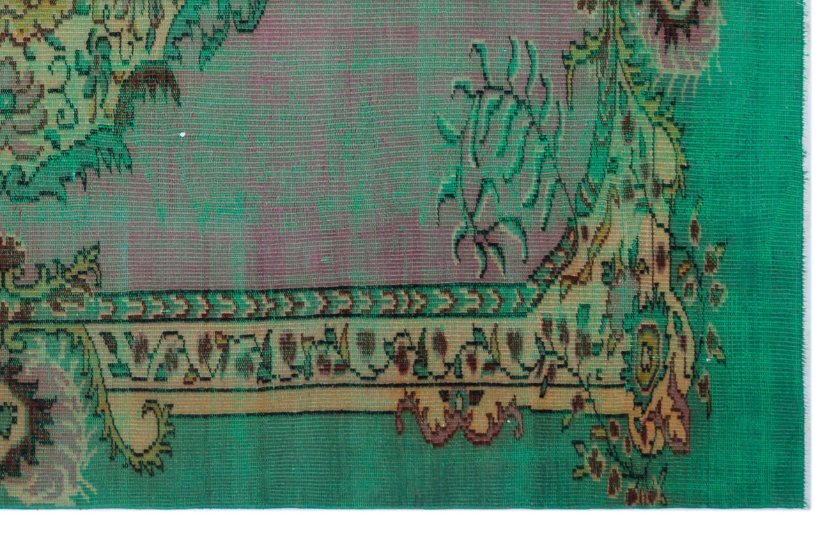 Distressed emerald green rug with a purple center and traditional floral border pattern on a white background.