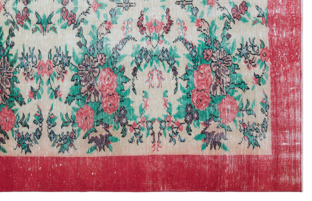 Beige rug with a distressed floral pattern in red and green, featuring a solid red border.