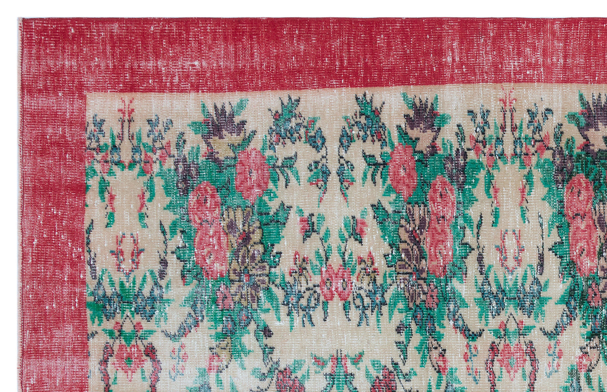 Distressed beige rug with a red border and a multi-colored floral pattern in red, green, and dark blue.