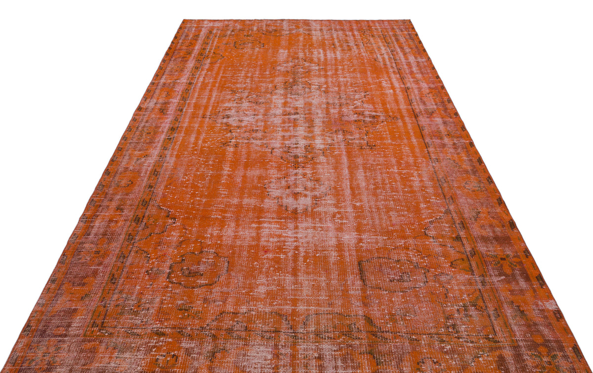 Burnt orange distressed area rug with a faded traditional medallion pattern and a bordered edge.