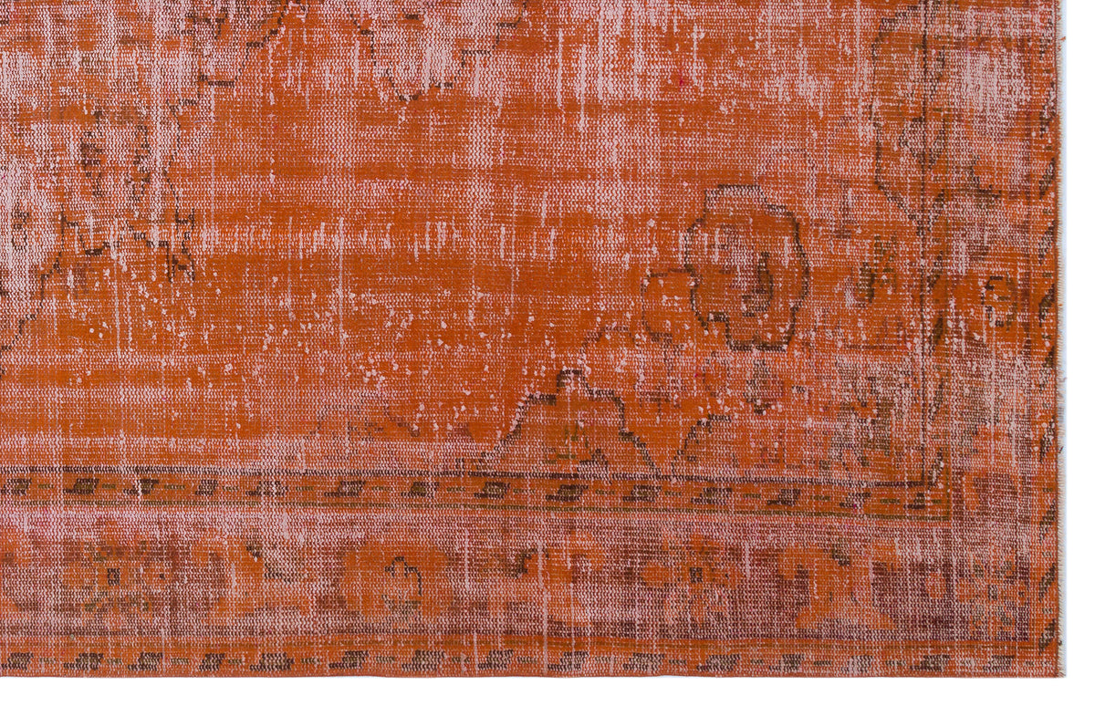 Burnt orange distressed rug with a faded traditional medallion pattern and a geometric border.