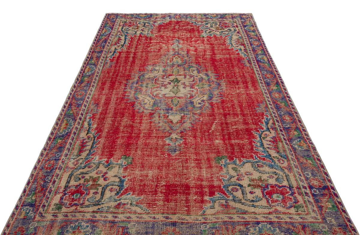 Distressed red traditional rug with a central medallion and blue and beige floral border patterns on a white background.