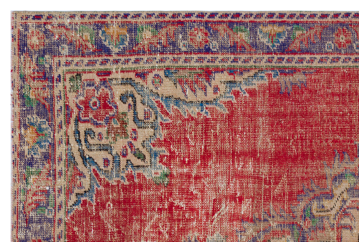 Distressed red, blue, and beige traditional rug with a floral medallion border and worn texture.
