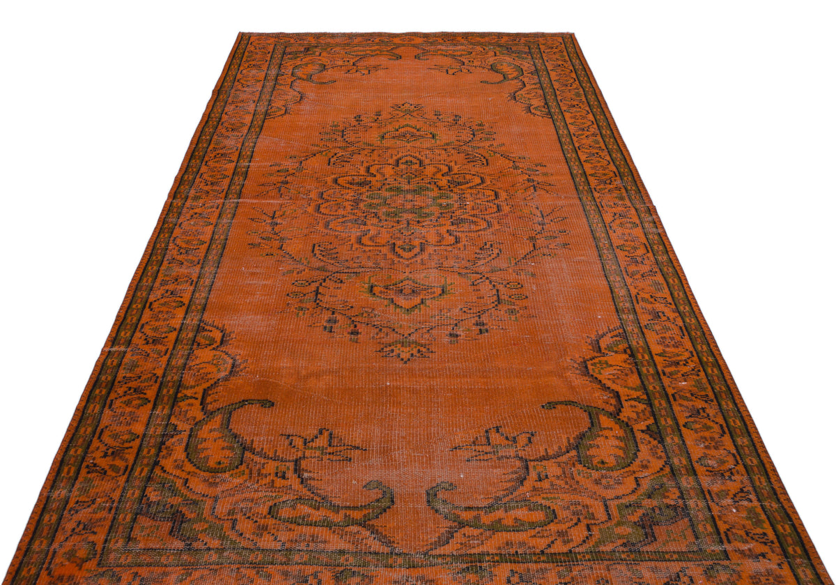 Burnt orange vintage rug with a central floral medallion and dark green border patterns on a white background.