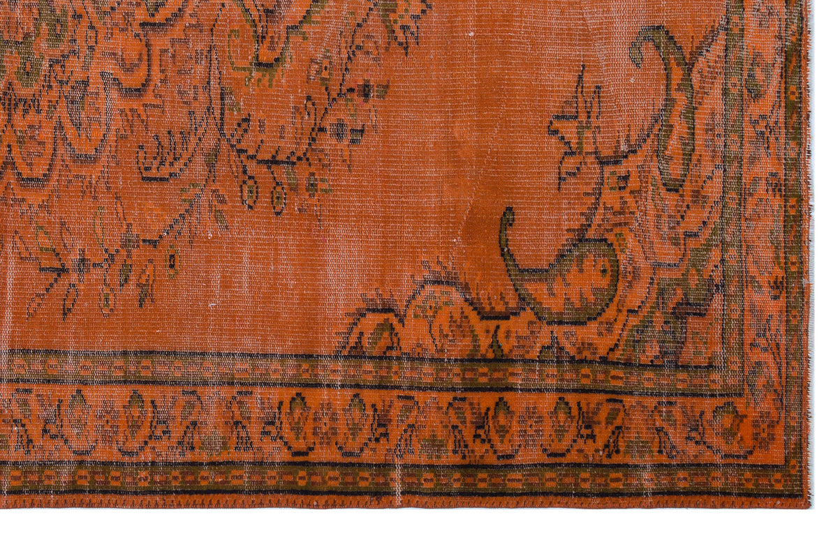 Burnt orange vintage-style rug with a distressed floral medallion pattern and a geometric border.