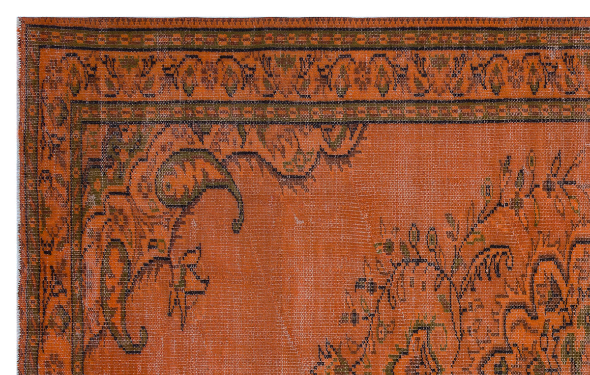 Burnt orange rug with a distressed traditional floral border and central medallion pattern in olive green and black.