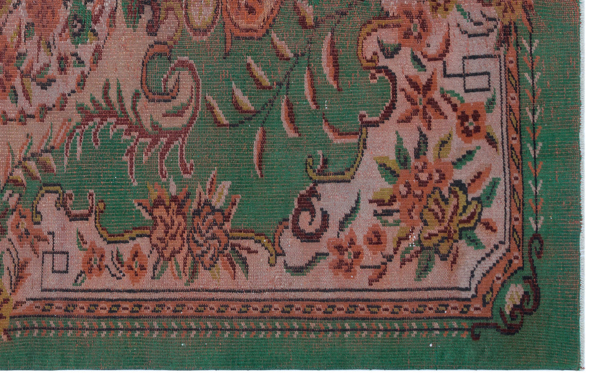 Green and dusty rose traditional rug with a floral vine pattern and a geometric border.