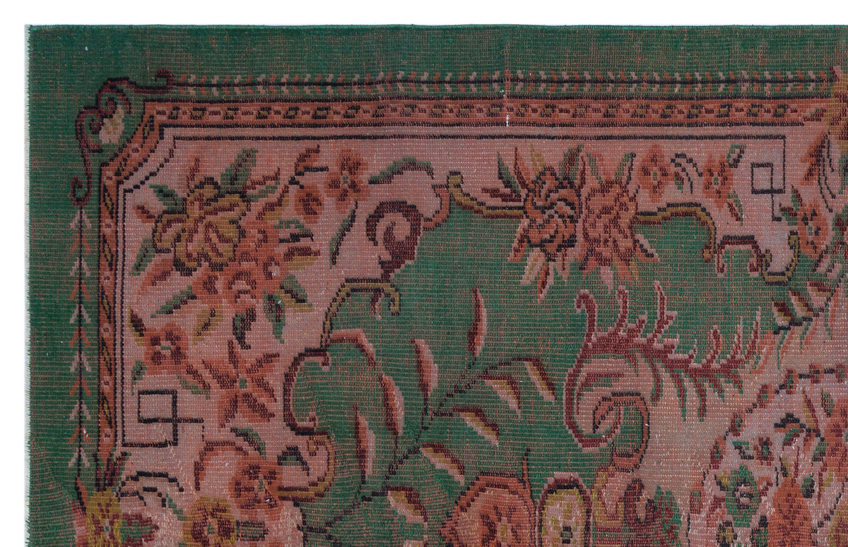 Traditional rug with a green border and a dusty rose field featuring intricate floral and vine motifs.