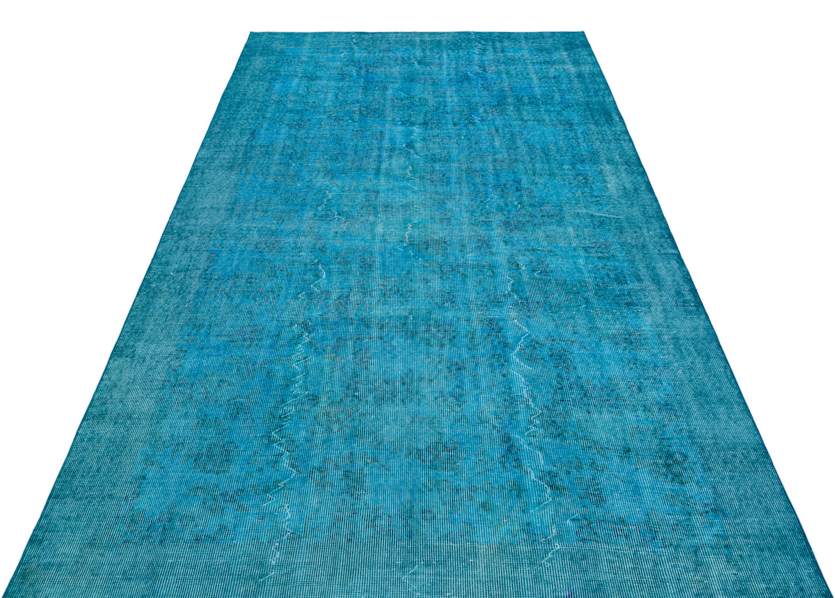 Bright turquoise vintage-style rug with a faded, distressed traditional medallion pattern on a white background.