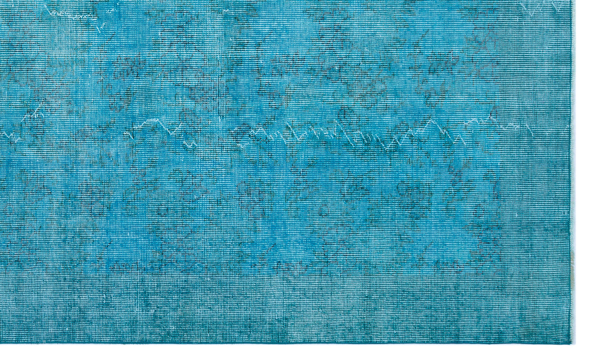 Bright turquoise rug with a distressed, faded traditional floral pattern and a visible woven texture.