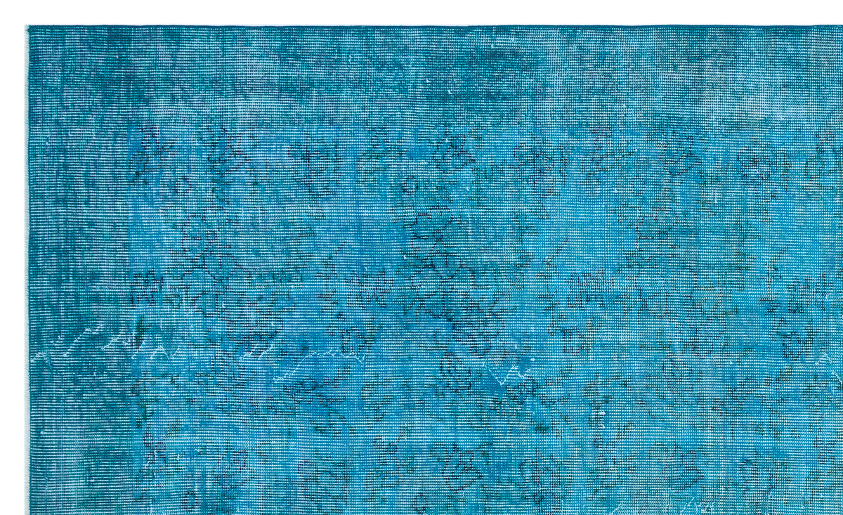 Teal distressed rug with a faint, dark blue traditional floral pattern.