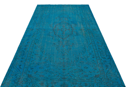 Load image 1 in gallery view. Bright blue vintage-style rug with a faded black central medallion and ornate border pattern on a white background.