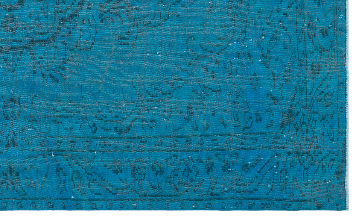 Teal rug with a distressed, dark grey traditional floral pattern and a bordered edge.