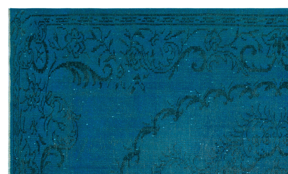 Teal rug with a dark blue distressed floral medallion pattern and a decorative border.