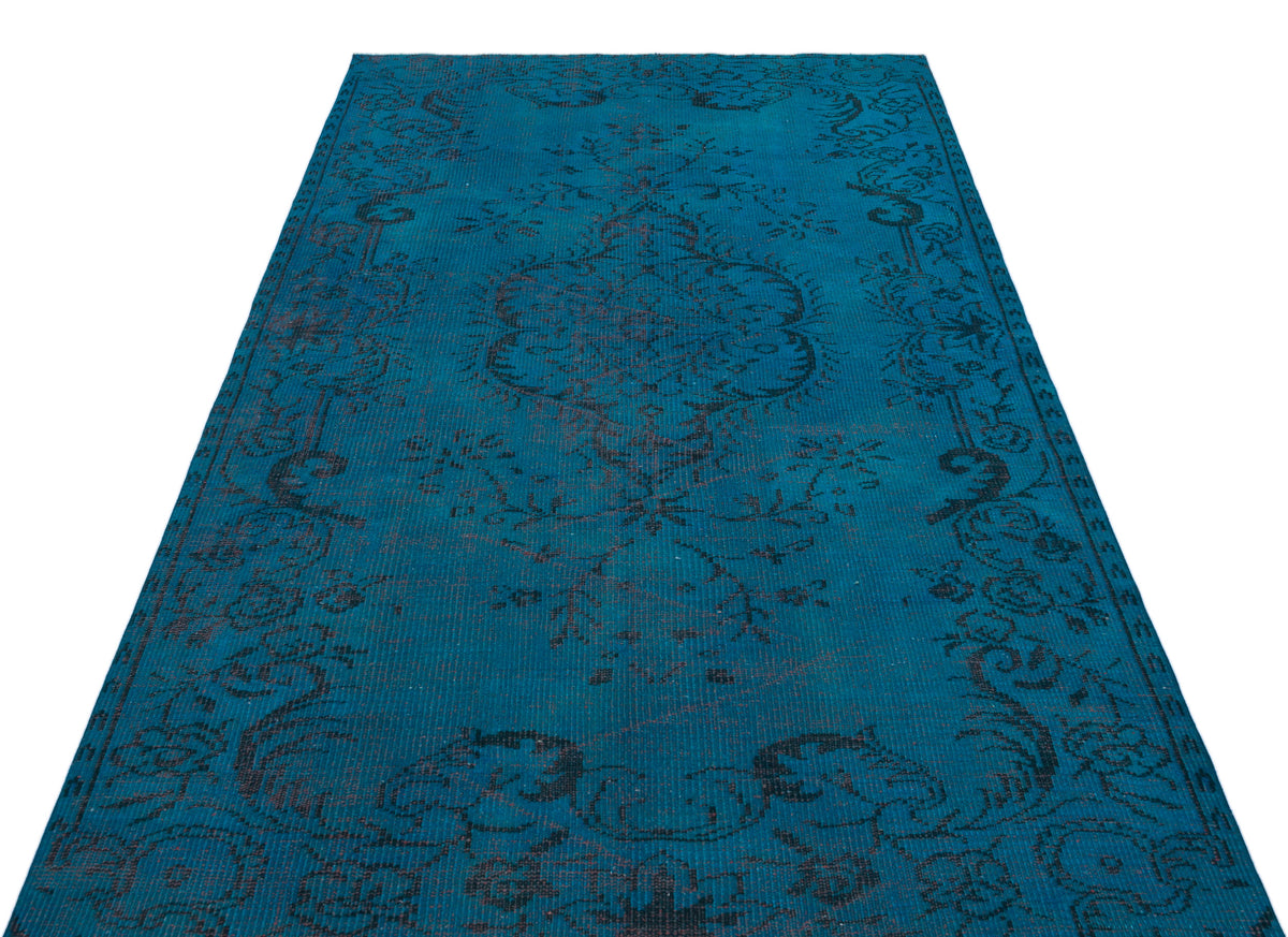 Teal rug with a distressed black floral medallion pattern on a white background.