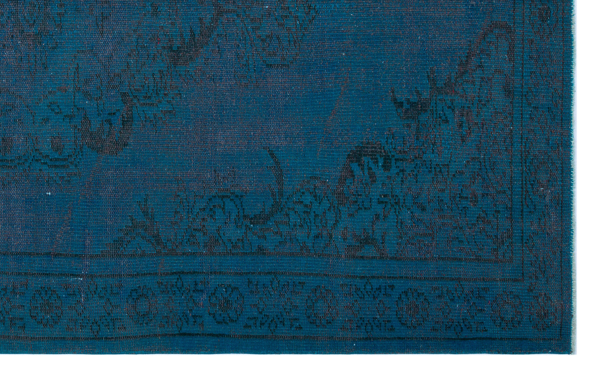 Deep teal rug with a dark, distressed floral medallion pattern and a decorative border.