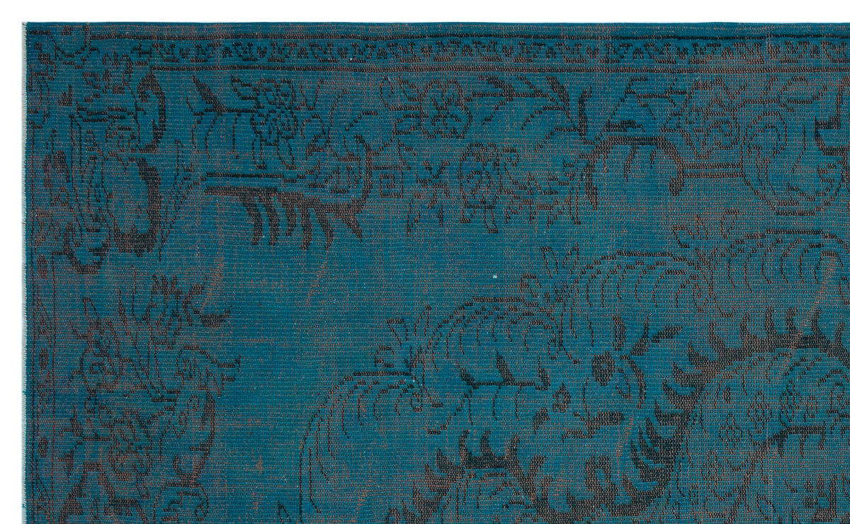 Teal rug with a dark charcoal floral and vine pattern and a decorative border.