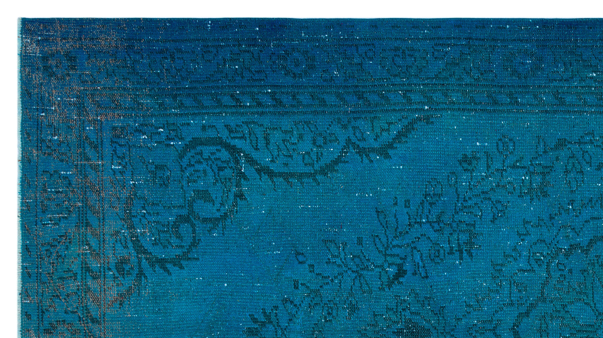 Deep blue distressed rug with a faded traditional floral border and ornate medallion pattern.