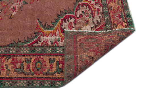 Load image 1 in gallery view. Brown traditional rug with a red, green, and gold floral border, shown with a corner folded over to reveal the backing.