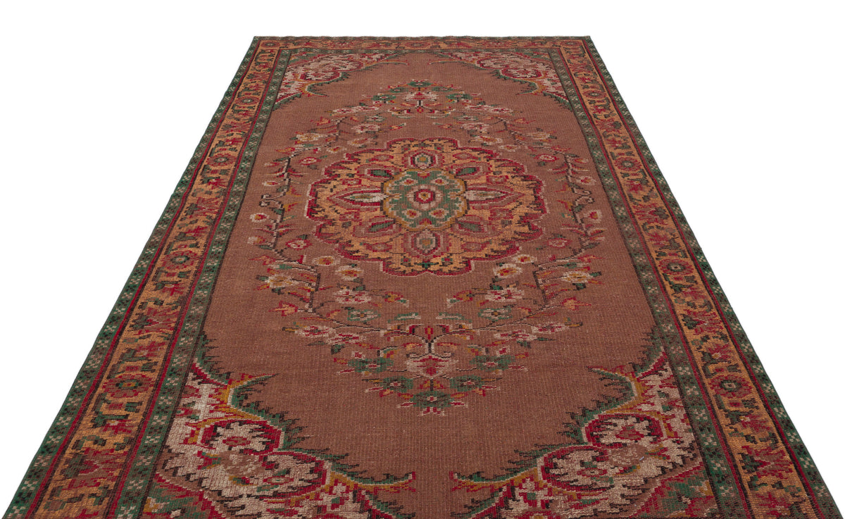 Brown traditional rug with a central floral medallion and ornate green and red border patterns.