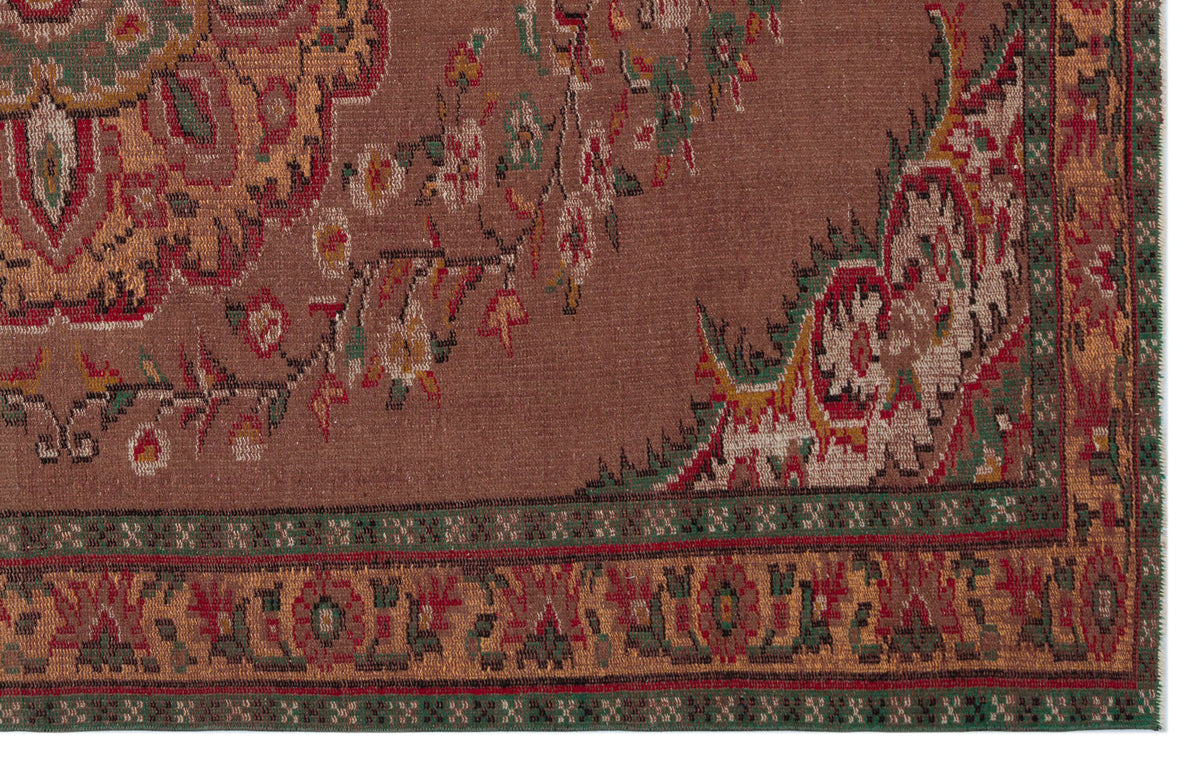 Brown traditional rug with a floral medallion pattern, intricate red and green border, and woven texture.