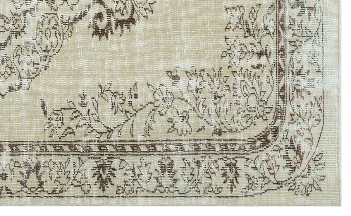 Beige rug with a distressed brown floral medallion pattern and a decorative geometric border.
