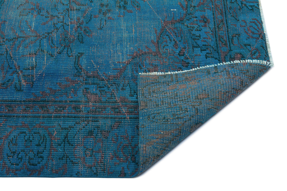 Teal and dark brown distressed traditional rug with a folded corner showing the woven backing.