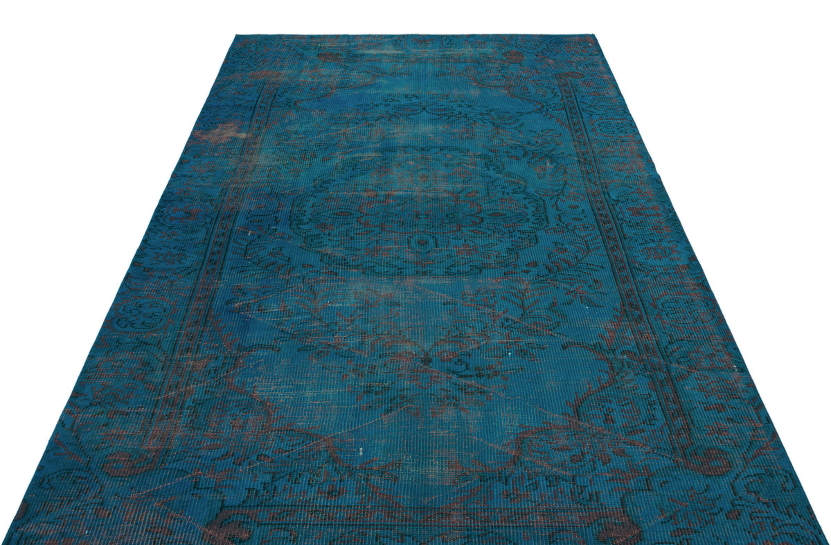 Teal and dark brown distressed vintage-style rug with a central floral medallion and ornate border.