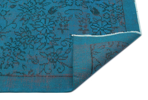 Load image 1 in gallery view. Teal rug with a dark floral pattern and a folded corner revealing the underside, isolated on a white background.