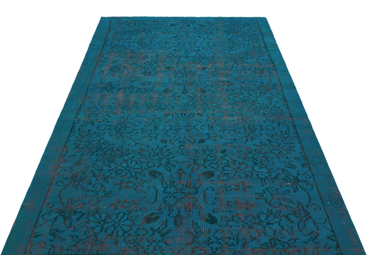 Teal rectangular rug with a dark, distressed floral medallion pattern on a white background.