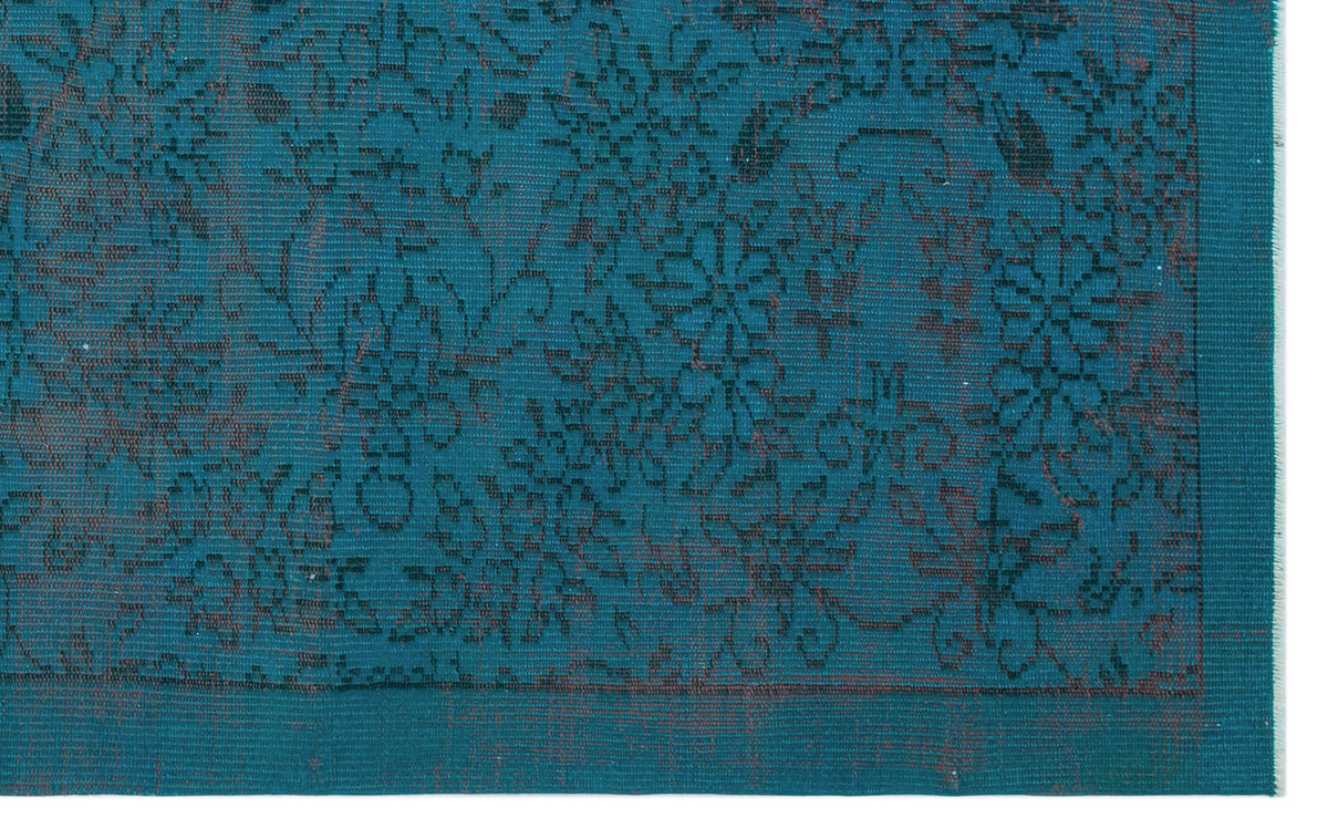 Teal rug with a dark floral pattern and a bordered edge.
