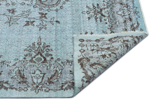 Load image 1 in gallery view. Light blue and brown distressed rug with a traditional floral medallion pattern, shown with a folded corner.