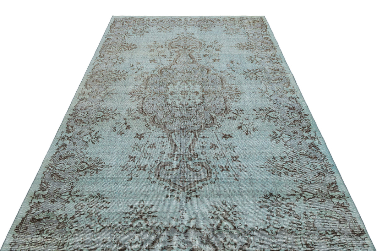 Light blue and brown distressed traditional rug with a central floral medallion and ornate border.