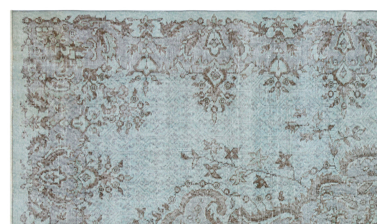 Light blue and brown distressed rug with a traditional floral medallion pattern.