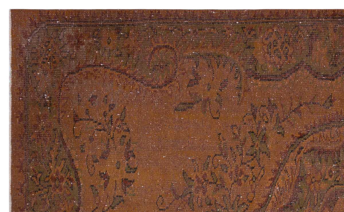 Rust-colored vintage rug with a distressed floral medallion pattern and dark brown border details.