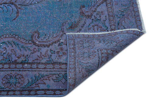 Load image 1 in gallery view. Blue and purple distressed traditional rug with a floral medallion pattern, shown with a corner folded over.