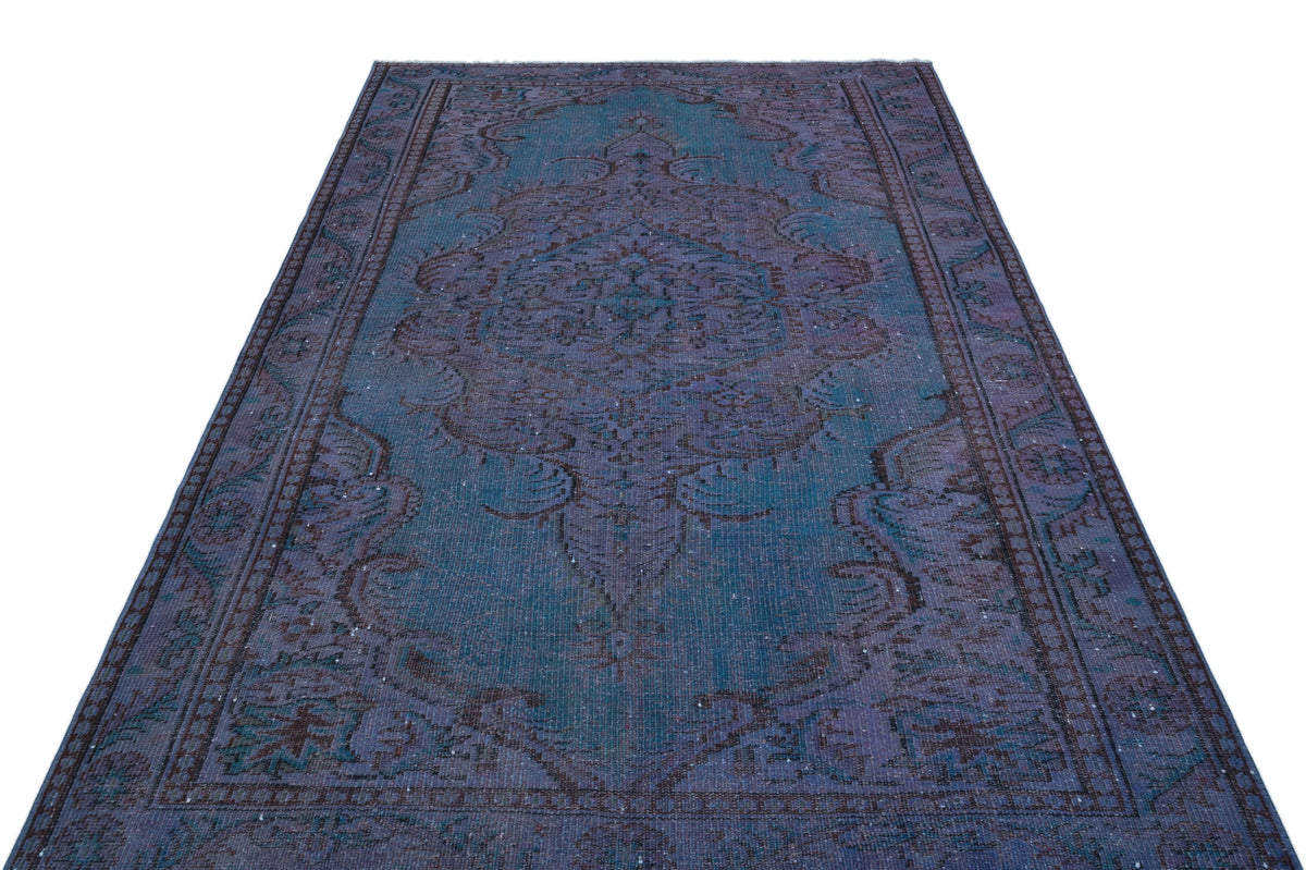 Distressed teal and purple vintage-style rug with a central medallion and ornate floral border.