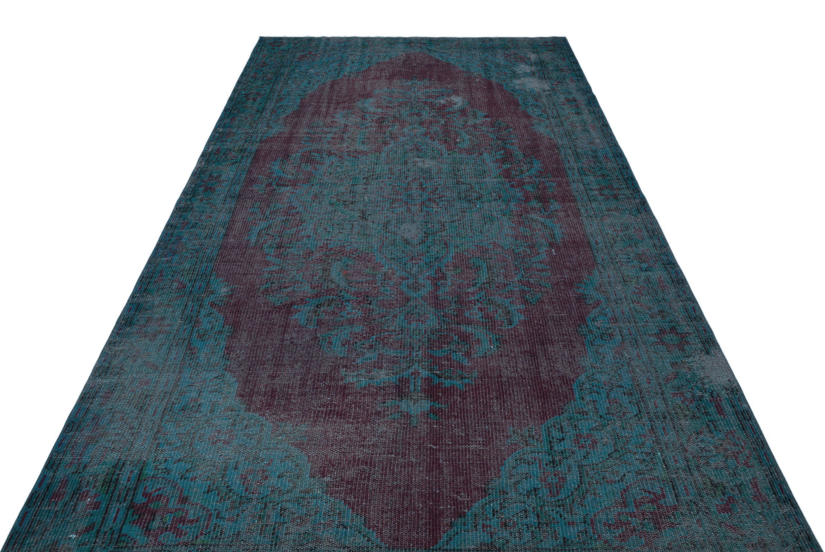 Distressed teal and deep plum vintage-style rug with a central floral medallion pattern on a white background.