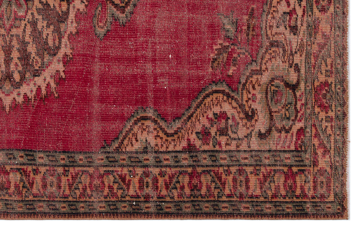 Distressed red vintage rug with a dark floral medallion pattern and a geometric border.