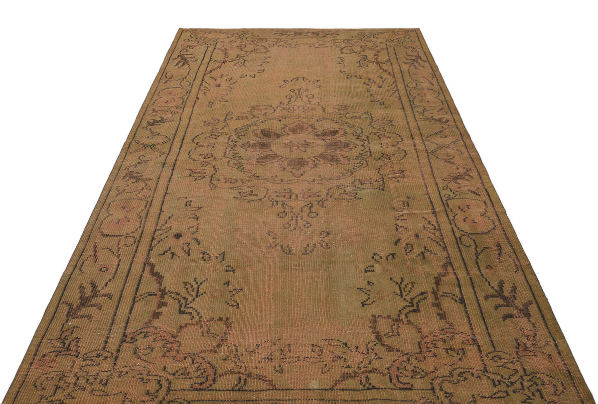 Distressed tan and brown vintage-style rug with a central floral medallion and ornate border pattern.