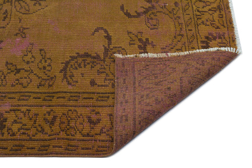 Load image 1 in gallery view. Mustard yellow and brown distressed rug with a floral medallion pattern, showing a folded corner with a purple underside.