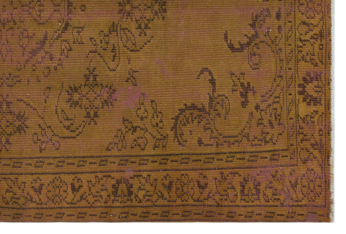 Ochre and brown traditional rug with a distressed floral medallion pattern and a geometric border.