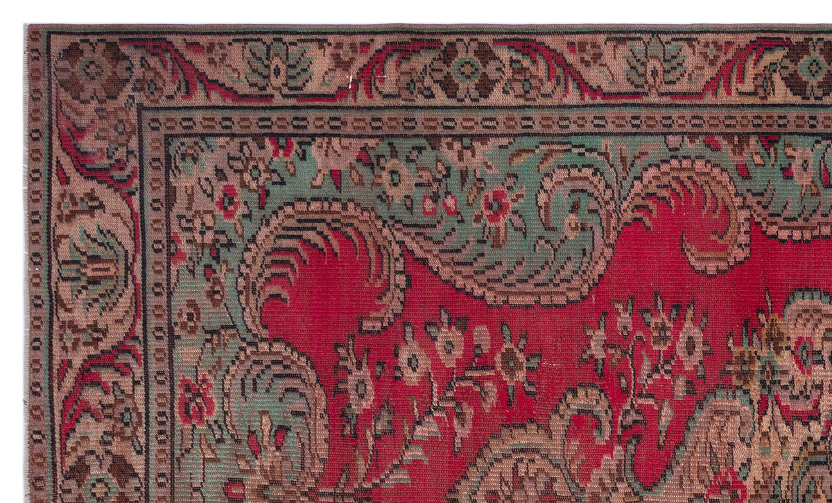 Traditional red rug with a green and brown floral paisley border and intricate botanical motifs.