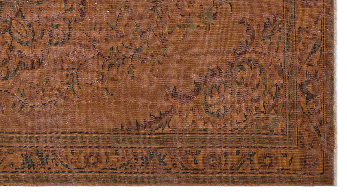 Rust-colored rug with a dark green floral medallion pattern and a geometric border.