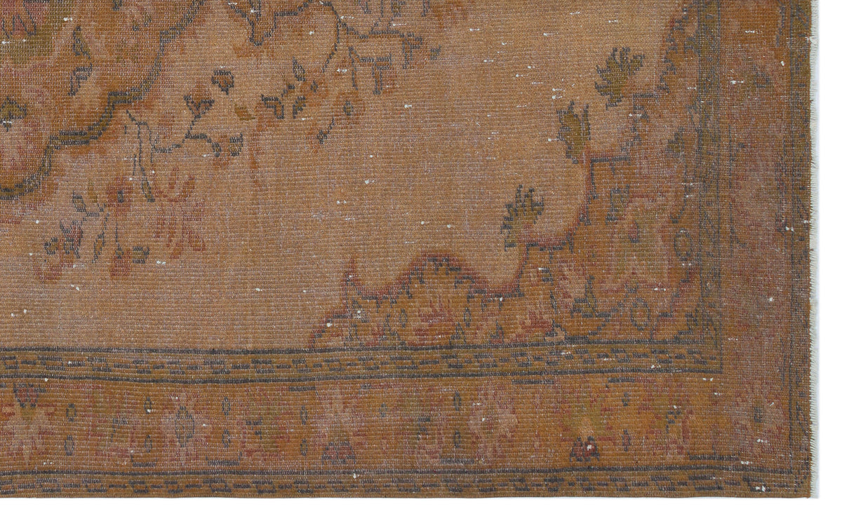 Distressed rust-orange rug with a faded floral medallion pattern and a geometric border on a white background.